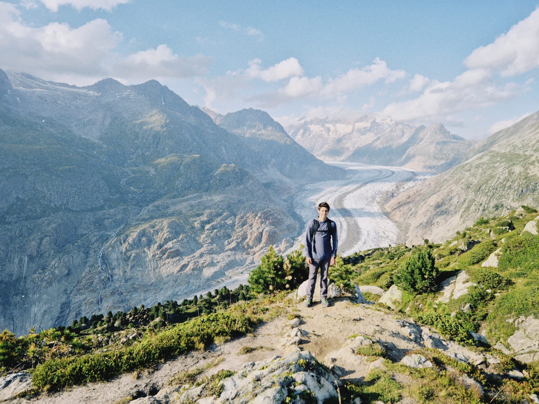 Pablo parado en el sendero, con el glaciar bajando por el valle