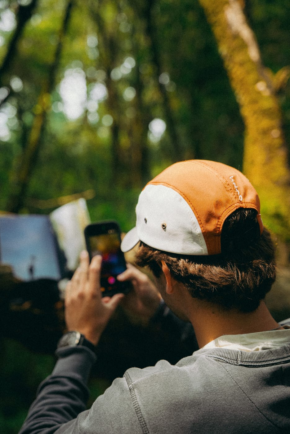 De lado, tomándole una foto a la revista con el celular; se ven los paneles naranja y crema